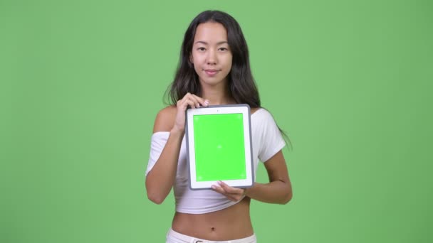 Młody szczęśliwy piękna kobieta wieloetnicznego myślenia podczas pokazywania cyfrowego tabletu — Wideo stockowe