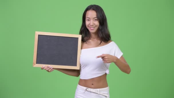 Молодая счастливая красивая многонациональная женщина держит доску и дает большие пальцы вверх — стоковое видео