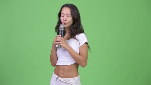 Молодая счастливая красивая многонациональная женщина поет с микрофоном — стоковое видео