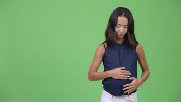 Молода щаслива вагітна багатоетнічна бізнес-леді показує щось — стокове відео