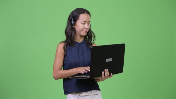 Young beautiful multi-ethnic businesswoman working as call center representative with laptop — Stock Video