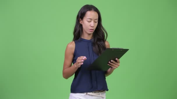 Jonge mooie multi-etnische zakenvrouw leiding tijdens het lezen op Klembord — Stockvideo