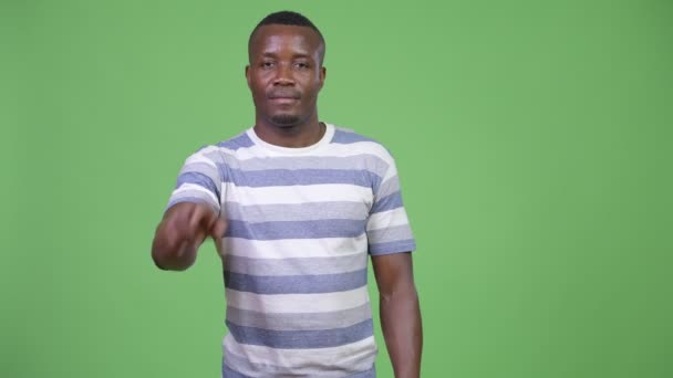 Joven hombre africano feliz sonriendo mientras señala a la cámara — Vídeos de Stock