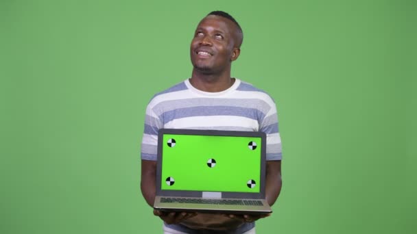 Щасливі африканських юнак думаючи, показуючи, що ноутбук — стокове відео