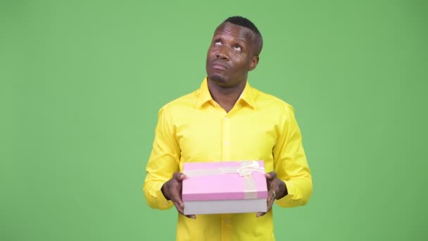 Junge glückliche afrikanische Geschäftsmann denken, während sie Geschenk-Box — Stockvideo