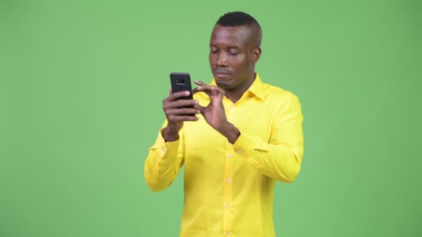 Молодой счастливый африканский бизнесмен пользуется телефоном и получает хорошие новости — стоковое видео