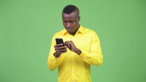 Joven empresario africano usando el teléfono y mirando sorprendido — Vídeos de Stock