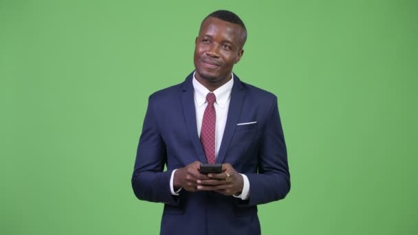 Junger glücklicher afrikanischer Geschäftsmann denkt beim Telefonieren — Stockvideo