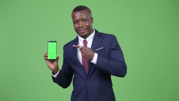 Молодий щасливі африканських бізнесмен, показуючи телефонів і даючи великі пальці — стокове відео