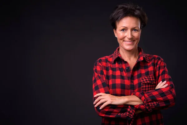 Siyah arka planda kısa saçlı, olgun, güzel bir kadın.