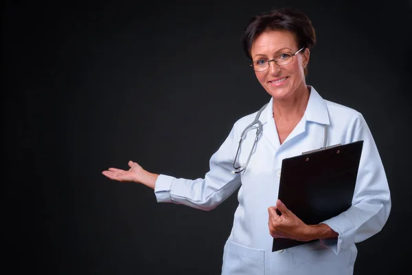 Reife schöne Ärztin mit kurzen Haaren gegen schwarzen Rücken — Stockfoto