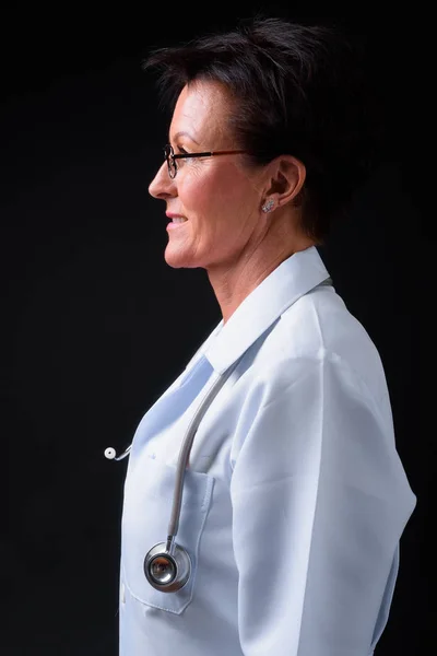 Äldre vacker kvinna läkare med kort hår mot svart rygg — Stockfoto