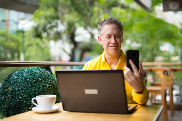 Зрелый человек с ноутбука компьютер и мобильный телефон — стоковое фото