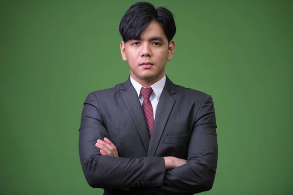 Mladý pohledný asijský podnikatel proti zeleným pozadím — Stock fotografie