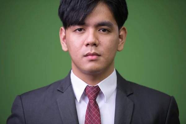 Giovane bello asiatico businessman contro verde sfondo — Foto Stock