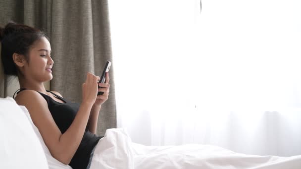 Mujer en la cama usando teléfono móvil — Vídeo de stock