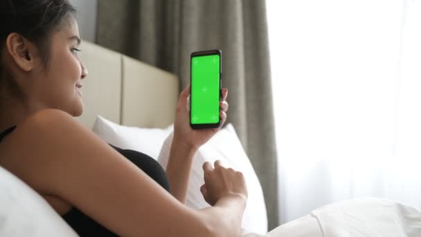Mujer en la cama usando el teléfono móvil con la llave verde del croma de la pantalla — Vídeo de stock
