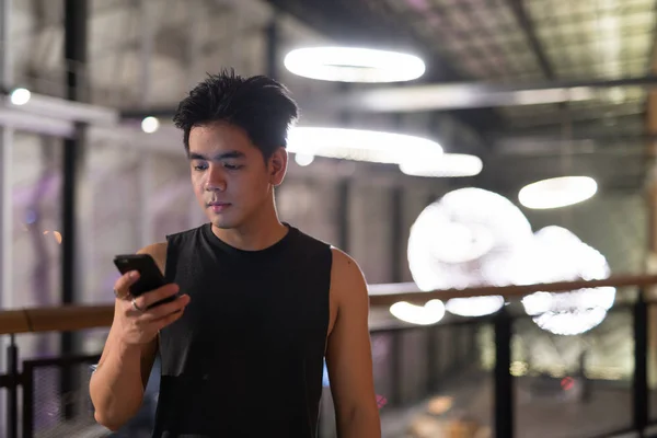 Όμορφος Ασίας νεαρός χρησιμοποιώντας τηλέφωνο στην πόλη ύπαιθρο τη νύχτα — Φωτογραφία Αρχείου