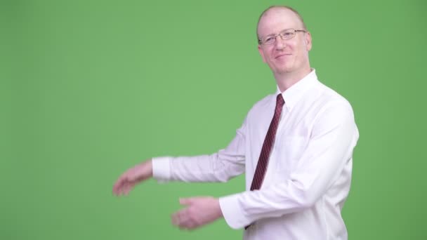 Щасливий зрілий лисий бізнесмен показує щось — стокове відео