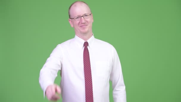 Щасливий зрілий лисий бізнесмен вказує на камеру — стокове відео