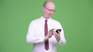 Olgun kel işadamı telefon kullanırken düşünme