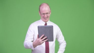 Mutlu olgun kel işadamı dijital tablet kullanma