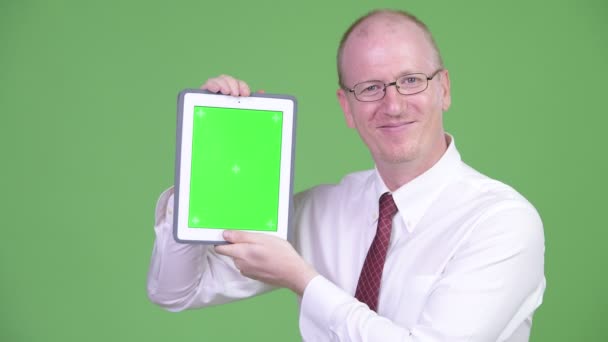 Щасливий зрілий лисий бізнесмен показує цифровий планшет — стокове відео