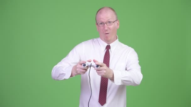 Щасливий зрілий лисий бізнесмен грає в ігри і виграє — стокове відео