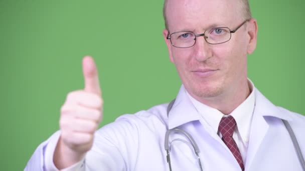Счастливый взрослый лысый врач думает, давая большие пальцы вверх — стоковое видео
