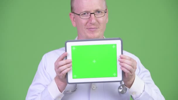 Щасливий зрілий лисий лікар показує цифровий планшет — стокове відео
