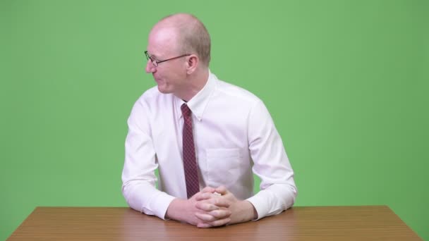 Злий зрілий лисий бізнесмен скаржиться комусь на дерев'яний стіл — стокове відео