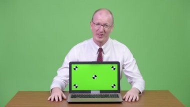 Hayal kırıklığına uğramış olgun kel işadamı kötü haber üstünde laptop ahşap masa karşı gösterilen
