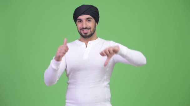 Молодий плутати бородатий індійського людина, вибираючи між великими пальцями і несхвалення — стокове відео