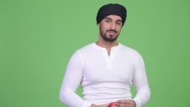 Jovem homem indiano barbudo feliz dando maçã vermelha — Vídeo de Stock