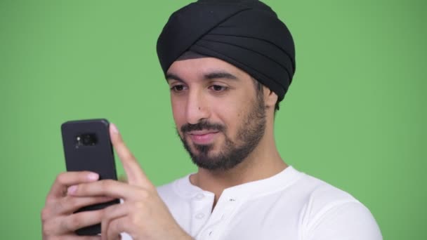 Молодой счастливый бородатый индиец улыбается во время разговора по телефону — стоковое видео