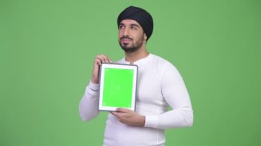 Mutlu genç Hintli adam dijital tablet gösterilen süre düşünme sakallı