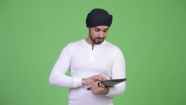 Jeune homme indien barbu heureux en utilisant une tablette numérique — Video