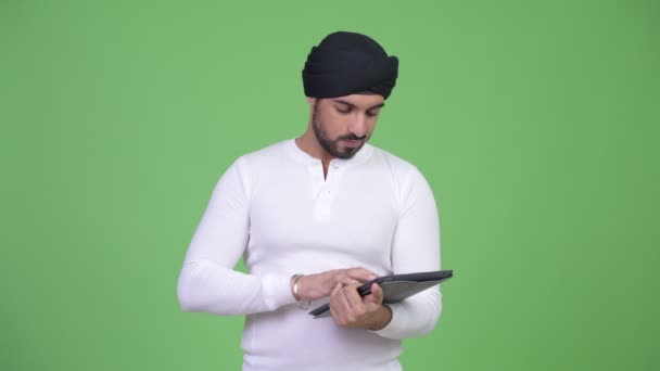 デジタル タブレットを使用している間考えて若いハンサムなひげを生やしたインド男 — ストック動画