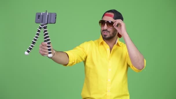 Young happy bearded Indian businessman vlogging with phone — Stock Video