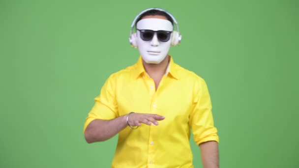 Молодой индийский бизнесмен в роли диджея в белой маске — стоковое видео