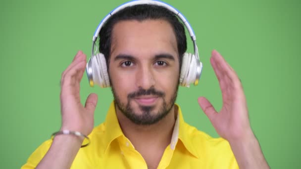 Jonge knappe bebaarde Indiase zakenman die luisteren naar muziek — Stockvideo
