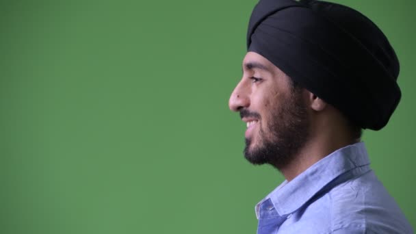 Vue du profil de jeune homme d'affaires indien barbu heureux portant turban et souriant — Video