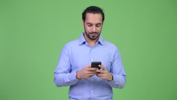 Молодой счастливый бородатый индийский бизнесмен по телефону — стоковое видео