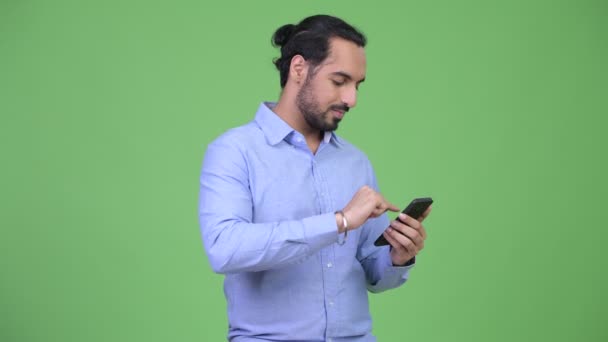 Joven feliz barbudo empresario indio usando el teléfono y recibiendo buenas noticias — Vídeos de Stock