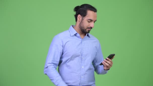Молодой бородатый индийский бизнесмен пользуется телефоном и выглядит удивленным — стоковое видео