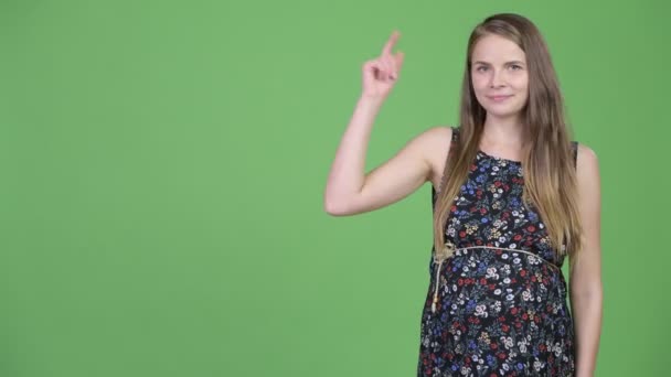 Ung glad gravid kvinna tänker samtidigt pekar uppåt — Stockvideo