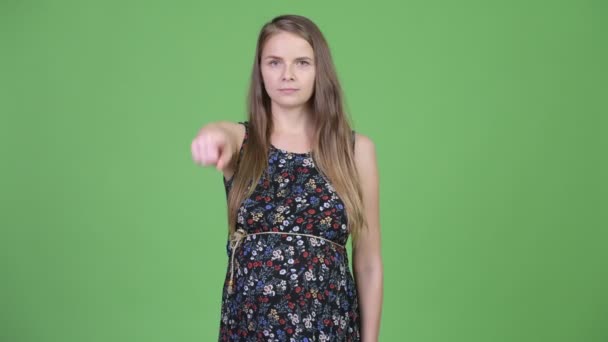 Молода красива вагітна жінка вказує на камеру — стокове відео