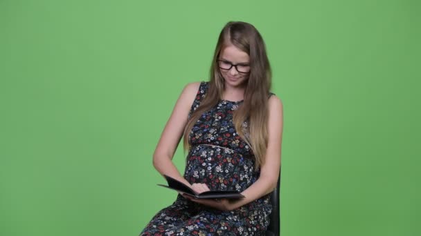 Νέοι όμορφη έγκυος γυναίκα διαβάζοντας το βιβλίο — Αρχείο Βίντεο
