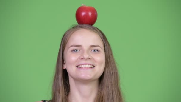 Jovem mulher bonita pensando com maçã em cima da cabeça — Vídeo de Stock