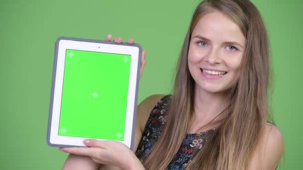 Junge glückliche schöne Frau zeigt digitales Tablet — Stockvideo